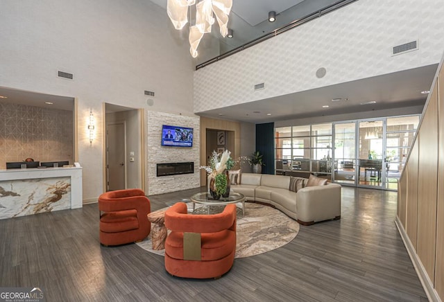 living area with a high ceiling, wood finished floors, a fireplace, and baseboards
