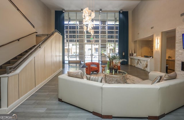 living area with a chandelier, a high ceiling, healthy amount of natural light, and a wall of windows