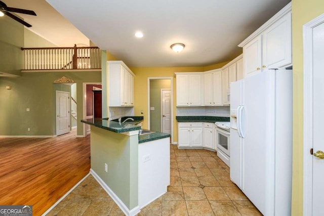 2430 Harbin Springs Cv, Dacula, GA 30019 - kitchen featuring white appliances, a peninsula, dark countertops, white cabinets, and ceiling fan