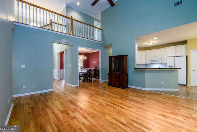 2430 Harbin Springs Cv, Dacula, GA 30019 - unfurnished living room featuring a high ceiling, ceiling fan, light wood-style flooring, baseboards, and a chandelier