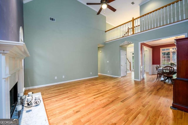 2430 Harbin Springs Cv, Dacula, GA 30019 - unfurnished living room with ceiling fan, high vaulted ceiling, a fireplace, light wood-type flooring, and baseboards