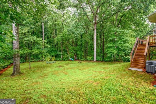 2430 Harbin Springs Cv, Dacula, GA 30019 - view of grassy yard featuring stairway, central AC unit, and a wooded view