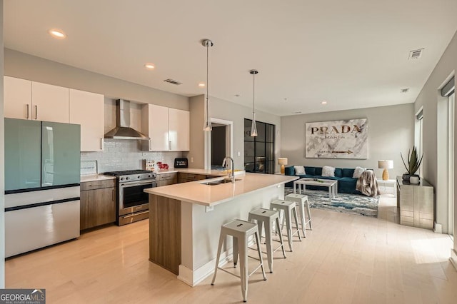 775 Juniper St NE Unit 612, Atlanta, GA 30308 - kitchen with stainless steel appliances, wall chimney range hood, a sink, light wood-style floors, and a breakfast bar area