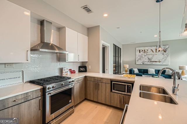 775 Juniper St NE Unit 612, Atlanta, GA 30308 - kitchen with stainless steel appliances, wall chimney range hood, a sink, open floor plan, and light countertops