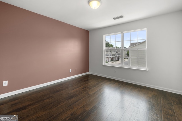 spare room featuring baseboards and dark wood-type flooring