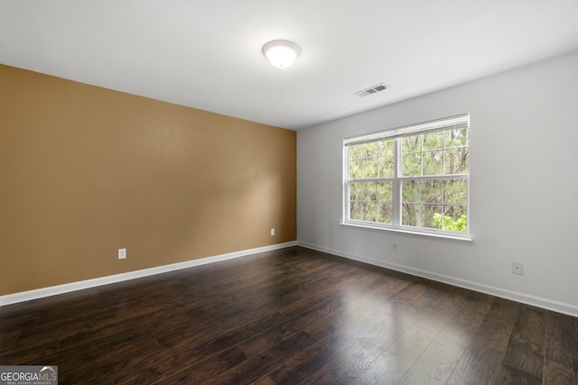 empty room featuring baseboards and dark wood-style flooring