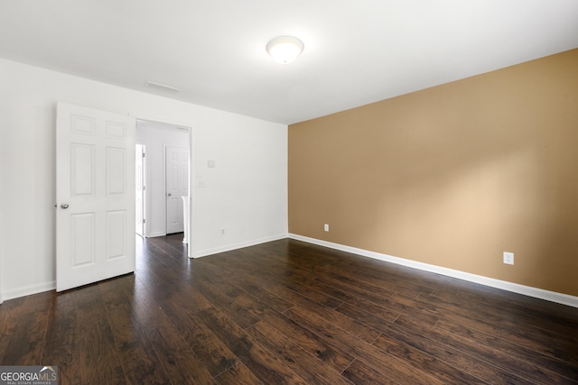 empty room with dark wood-style flooring and baseboards