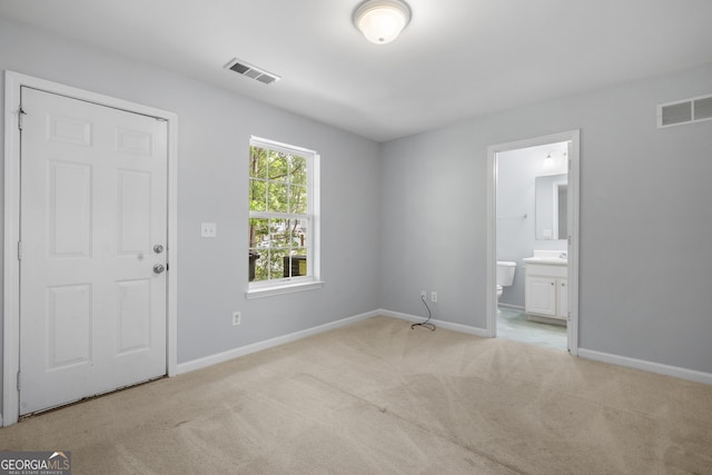unfurnished bedroom featuring light colored carpet, baseboards, and connected bathroom