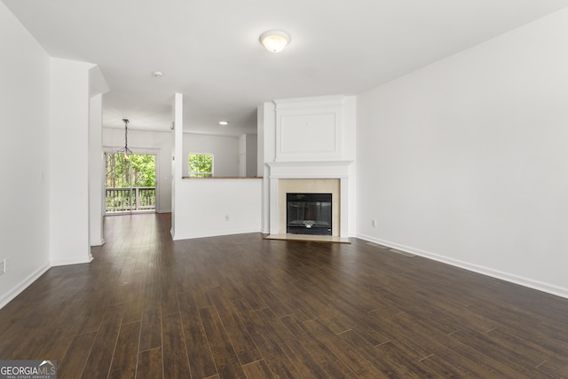 unfurnished living room featuring dark wood-style floors, baseboards, and a fireplace with flush hearth