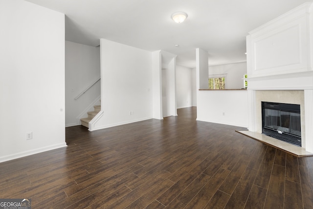 unfurnished living room with stairs, dark wood-type flooring, a premium fireplace, and baseboards