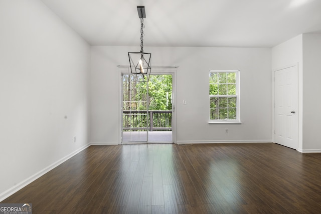 unfurnished room featuring dark wood-type flooring, baseboards, and a chandelier