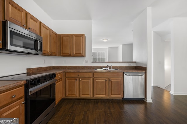 kitchen featuring appliances with stainless steel finishes, a sink, dark wood finished floors, and brown cabinetry