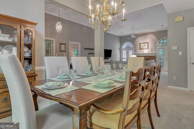 dining space featuring light carpet, ceiling fan, a chandelier, and baseboards