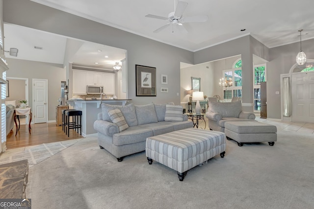 living room featuring crown molding, light carpet, a ceiling fan, a chandelier, and baseboards