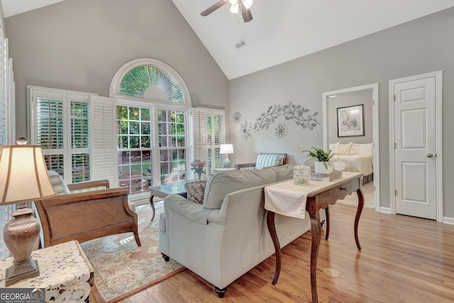 living area with high vaulted ceiling, a ceiling fan, and light wood-style floors