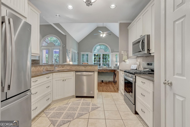 kitchen featuring stainless steel appliances, a sink, a ceiling fan, tasteful backsplash, and white cabinetry