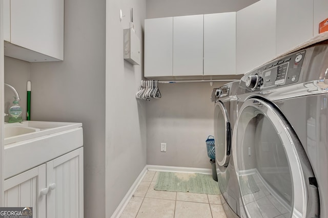 clothes washing area featuring washer and dryer, cabinet space, light tile patterned flooring, and baseboards