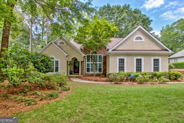 view of front of home featuring a front lawn, stucco siding, and stone siding