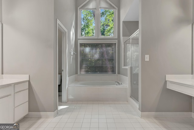 full bath with vanity, a stall shower, tile patterned flooring, a garden tub, and baseboards