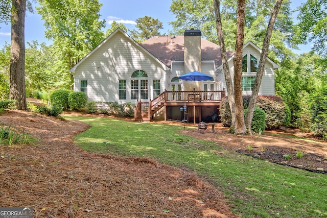rear view of house with stairs, a chimney, a wooden deck, a lawn, and a shingled roof