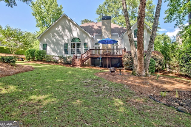 rear view of house with stairway, a wooden deck, a chimney, a yard, and a shingled roof