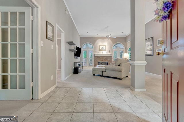 living room with light carpet, ceiling fan, a fireplace, ornamental molding, and light tile patterned flooring