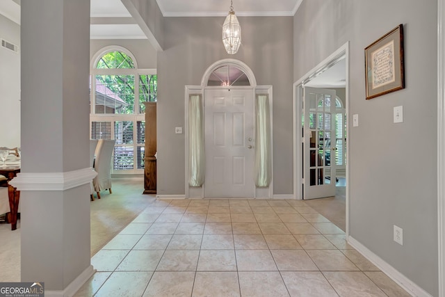 foyer entrance with a high ceiling, a chandelier, ornamental molding, and baseboards