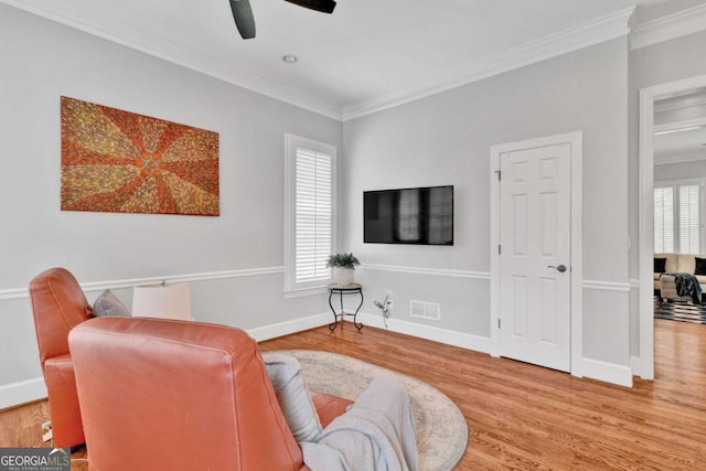 sitting room featuring crown molding, wood finished floors, a ceiling fan, and plenty of natural light