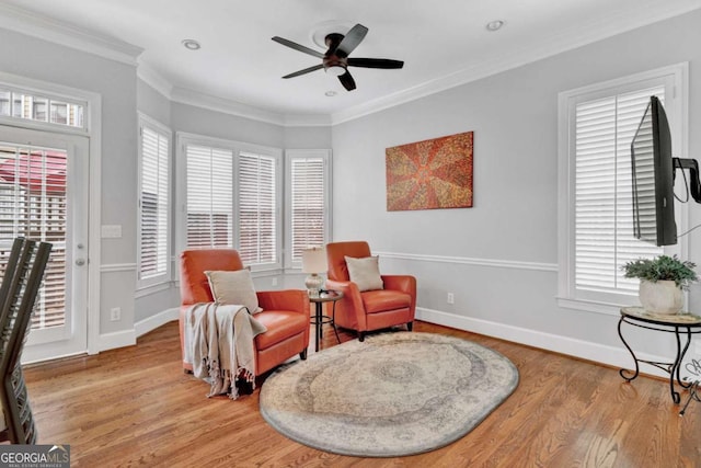 sitting room featuring plenty of natural light, light wood-style flooring, a ceiling fan, baseboards, and crown molding