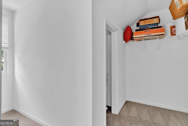 corridor featuring carpet floors, lofted ceiling, and baseboards