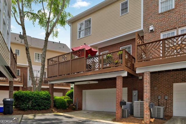 view of building exterior featuring an attached garage, central AC, and driveway