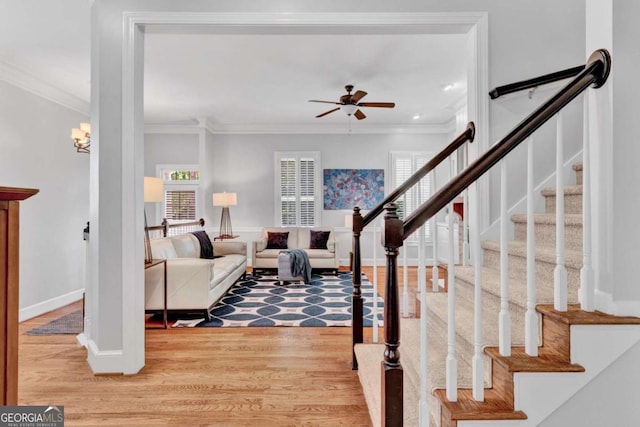 foyer featuring a ceiling fan, crown molding, light wood-type flooring, stairway, and baseboards