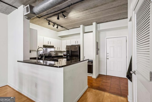 800 Peachtree St NE Unit 2304, Atlanta, GA 30308 - kitchen with black appliances, under cabinet range hood, a peninsula, dark countertops, and white cabinetry