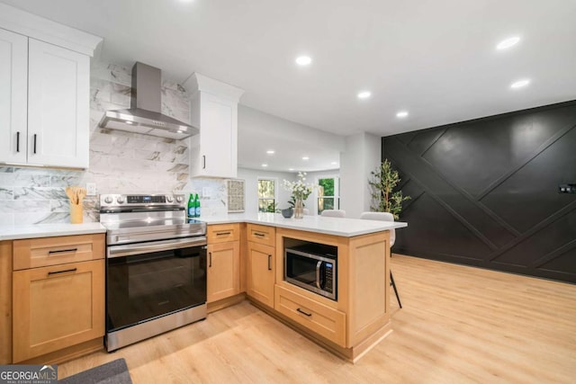 2781 Long Way, Decatur, GA 30032 - kitchen with appliances with stainless steel finishes, wall chimney exhaust hood, light wood finished floors, a peninsula, and light countertops