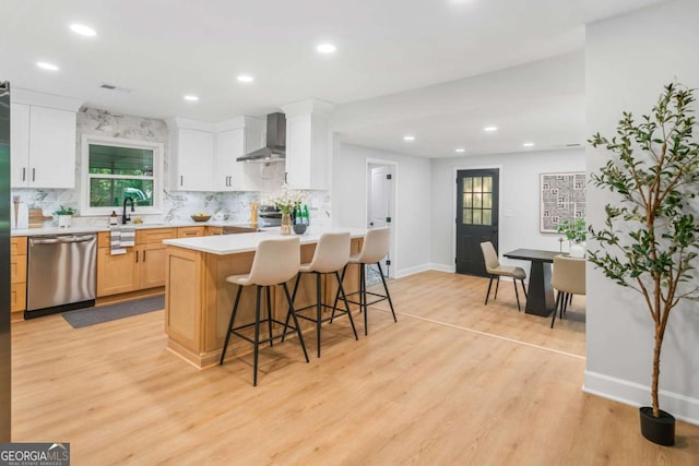 2781 Long Way, Decatur, GA 30032 - kitchen with stainless steel appliances, wall chimney exhaust hood, a kitchen bar, light wood-type flooring, and backsplash