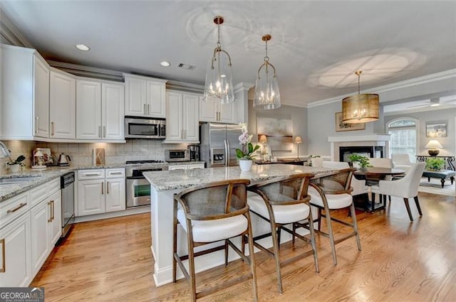 7435 Jamestown Dr, Alpharetta, GA 30005 - kitchen with stainless steel appliances, decorative backsplash, a kitchen island, white cabinets, and ornamental molding