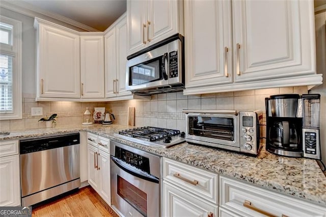 7435 Jamestown Dr, Alpharetta, GA 30005 - kitchen with appliances with stainless steel finishes, white cabinetry, tasteful backsplash, light stone countertops, and light wood-style floors