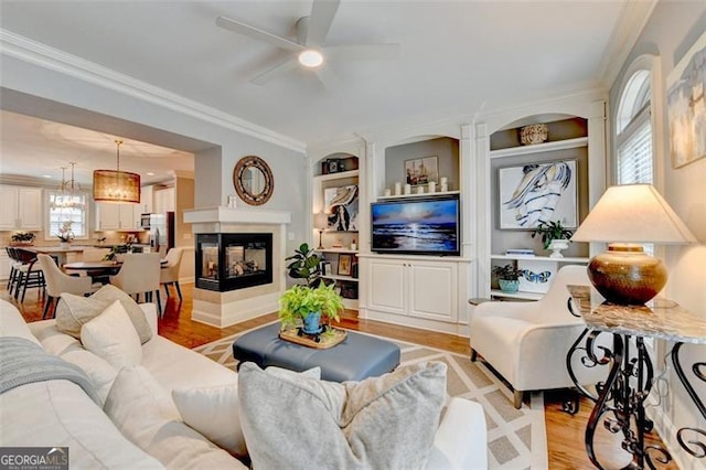 7435 Jamestown Dr, Alpharetta, GA 30005 - living area with light wood-style floors, crown molding, ceiling fan, built in features, and a multi sided fireplace
