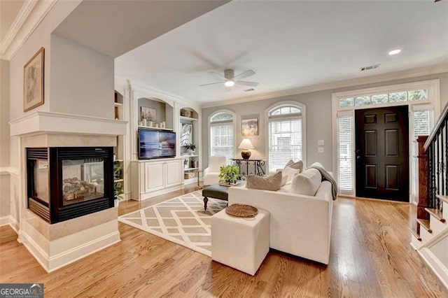 7435 Jamestown Dr, Alpharetta, GA 30005 - living room with stairs, ornamental molding, ceiling fan, light wood-style flooring, and a multi sided fireplace