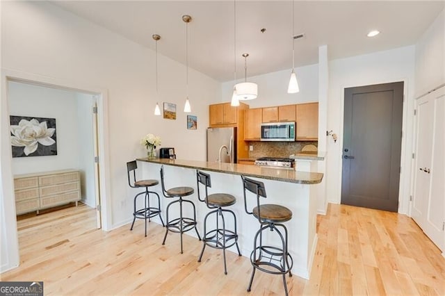 1430 Dresden Dr NE Unit 225, Atlanta, GA 30319 - kitchen with stainless steel appliances, a breakfast bar area, light wood-style floors, decorative backsplash, and a peninsula