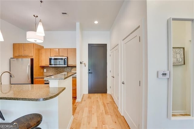 1430 Dresden Dr NE Unit 225, Atlanta, GA 30319 - kitchen with stainless steel appliances, light wood finished floors, decorative light fixtures, backsplash, and stone counters