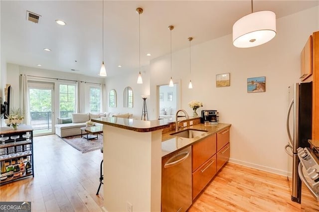 1430 Dresden Dr NE Unit 225, Atlanta, GA 30319 - kitchen with a sink, brown cabinetry, stainless steel appliances, a peninsula, and dark stone counters