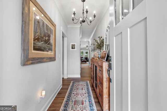 hall featuring dark wood finished floors, a chandelier, ornamental molding, and baseboards