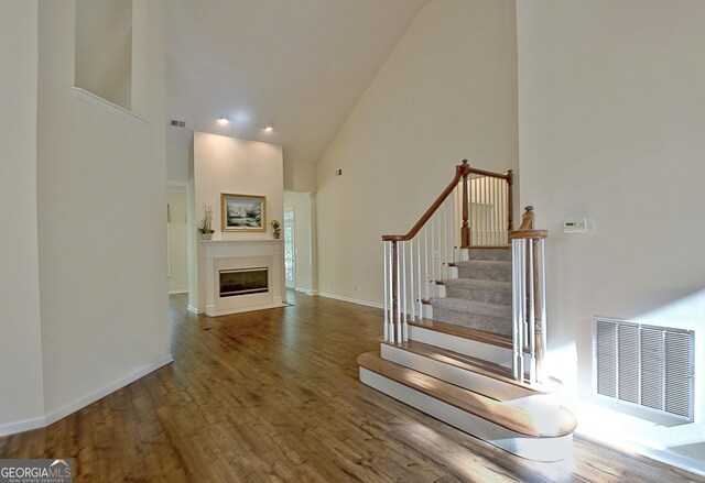 44 Arbor Way, Newnan, GA 30265 - stairs featuring high vaulted ceiling, wood finished floors, a fireplace with flush hearth, and baseboards