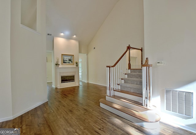 44 Arbor Way, Newnan, GA 30265 - stairs featuring high vaulted ceiling, wood finished floors, and a fireplace with flush hearth
