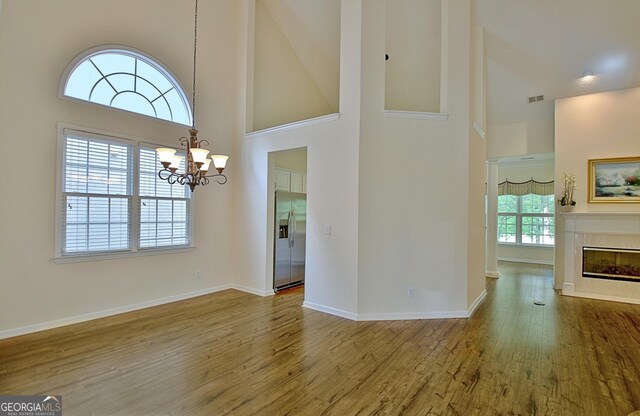 44 Arbor Way, Newnan, GA 30265 - unfurnished dining area with high vaulted ceiling, wood finished floors, a chandelier, baseboards, and a glass covered fireplace