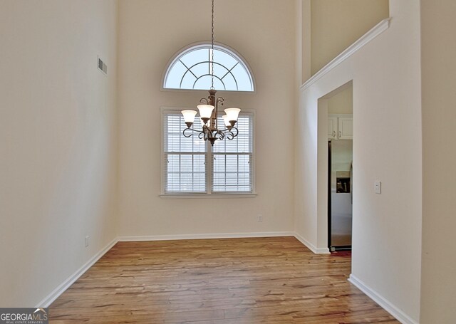 44 Arbor Way, Newnan, GA 30265 - unfurnished dining area with a chandelier, plenty of natural light, light wood-style floors, a high ceiling, and baseboards