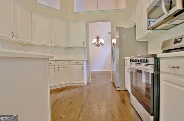 44 Arbor Way, Newnan, GA 30265 - kitchen with appliances with stainless steel finishes, a chandelier, white cabinets, light wood-type flooring, and light countertops
