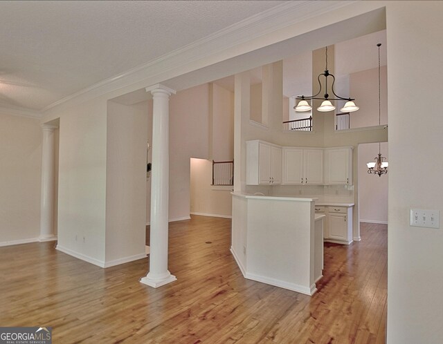 44 Arbor Way, Newnan, GA 30265 - kitchen with a chandelier, white cabinets, light countertops, ornamental molding, and light wood-style floors