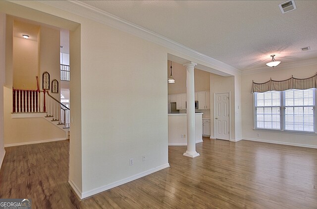 44 Arbor Way, Newnan, GA 30265 - unfurnished living room with ornamental molding, wood finished floors, decorative columns, baseboards, and a textured ceiling